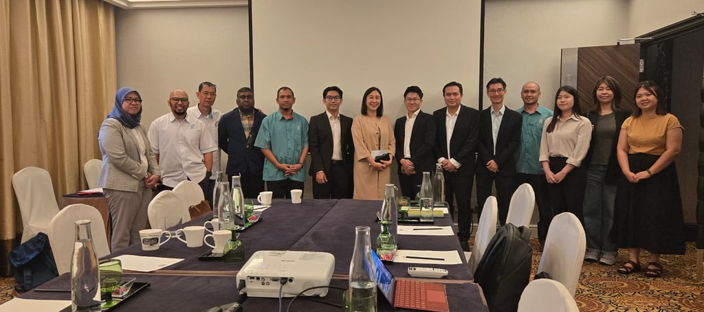 Professional group posing for a corporate business meeting in a conference room with a projector.