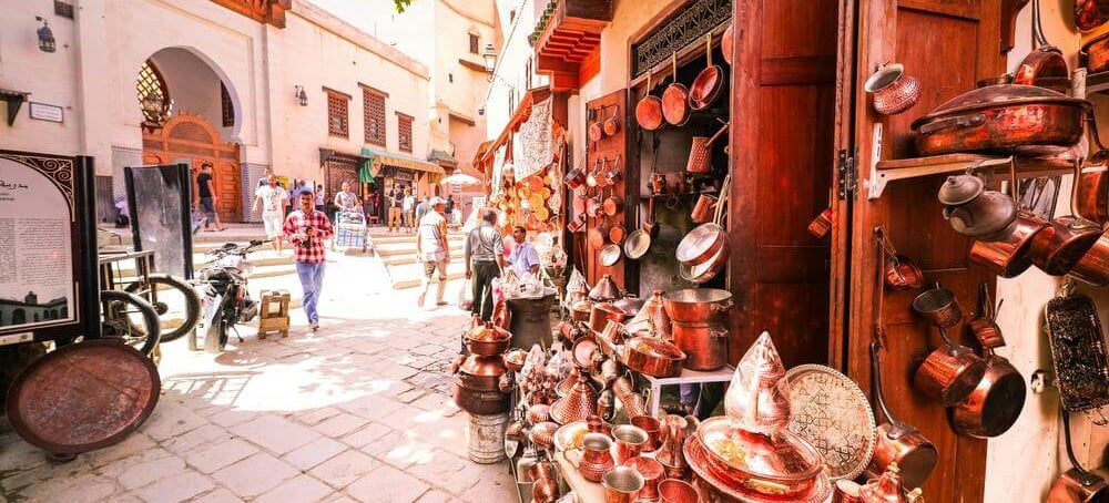 Busy street in Moroccan medina with traditional copper crafts and local shops