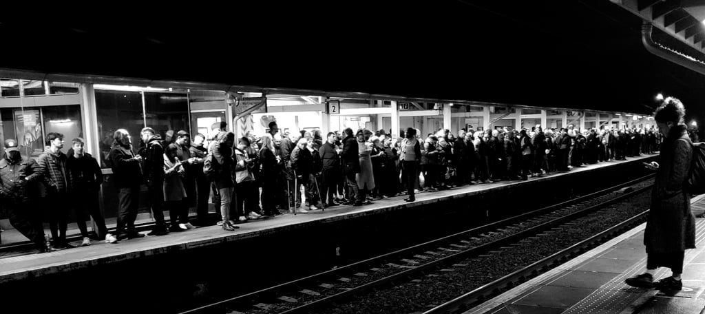 Two platforms at a train station, with one person on the nearside and hundreds on the other.
