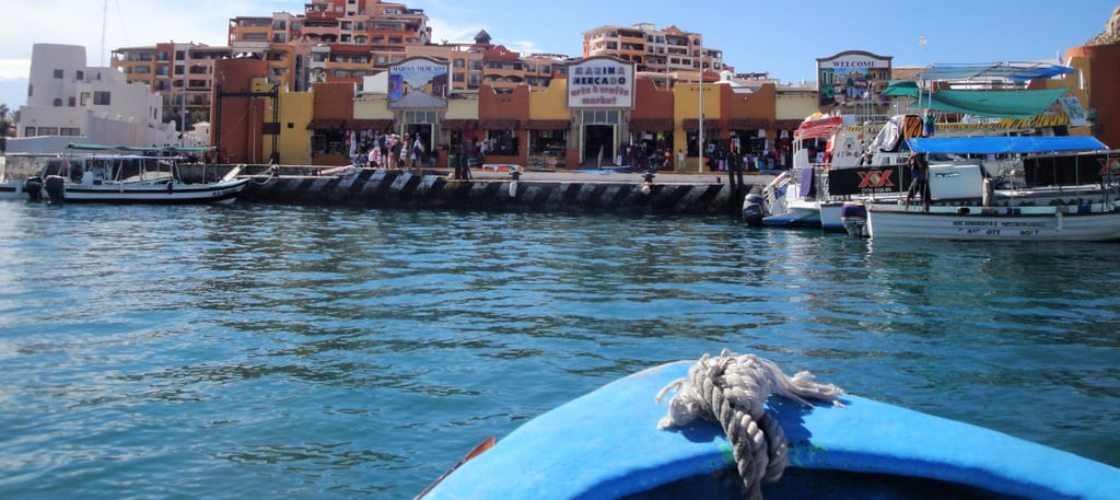 Vista do pier de Cabo San Lucas a partir do barco, com o mar cristalino e a costa ao fundo