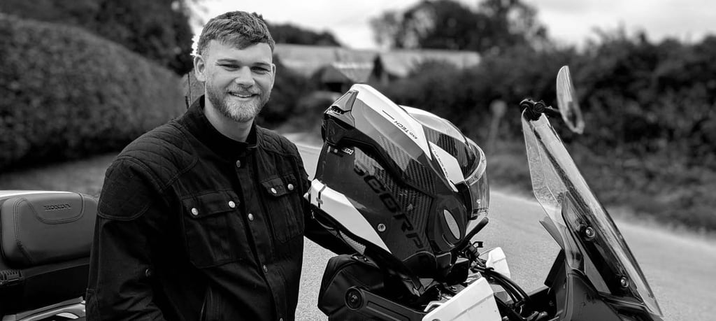Paul standling alongside his Honda Transalp motorcycle at the roadside of a country lane