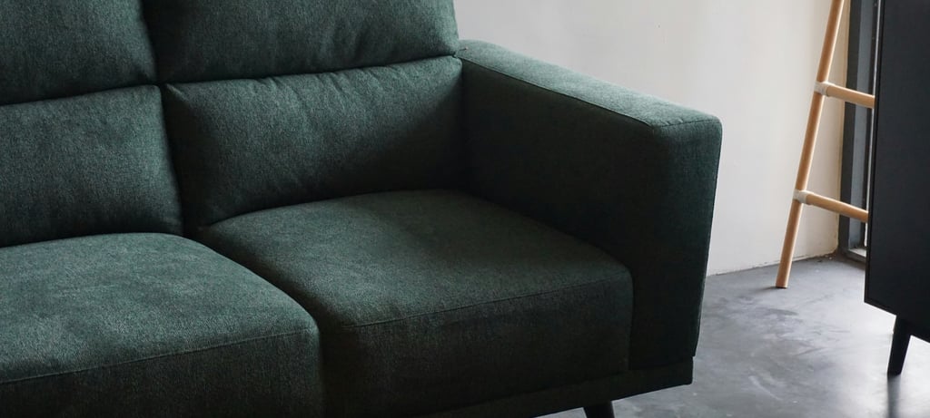 Green upholstered sofa in a modern room promoting fibre‑safe upholstery and mattress cleaning.