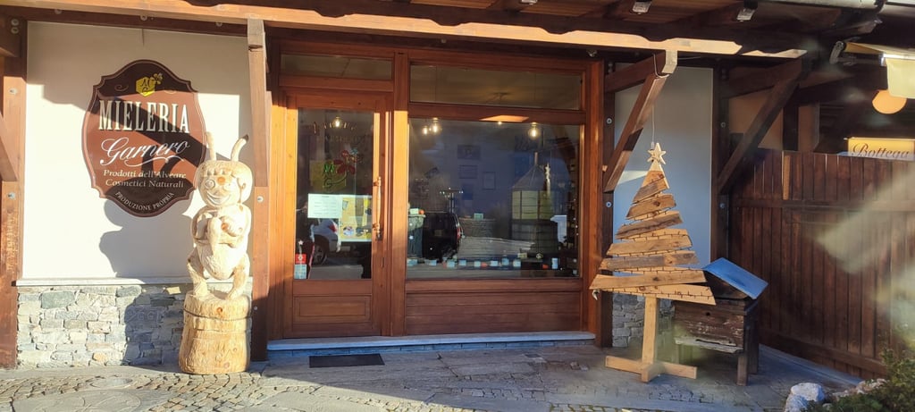 ingresso e vetrina del negozio di Sampeyre della Mieleria Garnero, con insegna e ape di legno