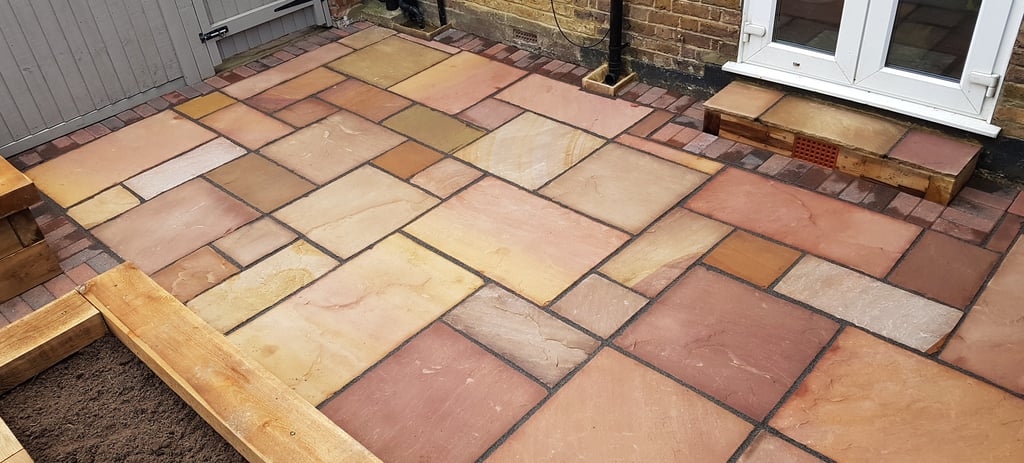 Colourful sandstone patio with raised wooden timber planter seating