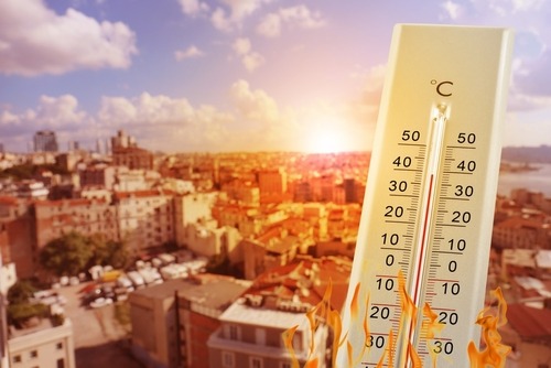 Thermometer showing high temperatures over a sun-drenched city during a summer heatwave.