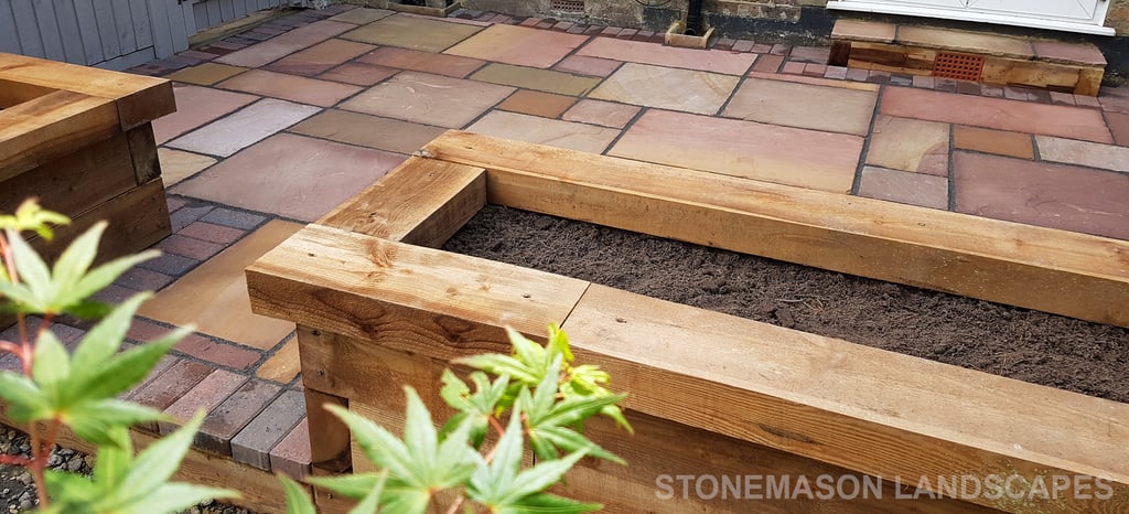 Colourful sandstone patio with raised wooden timber planter seating