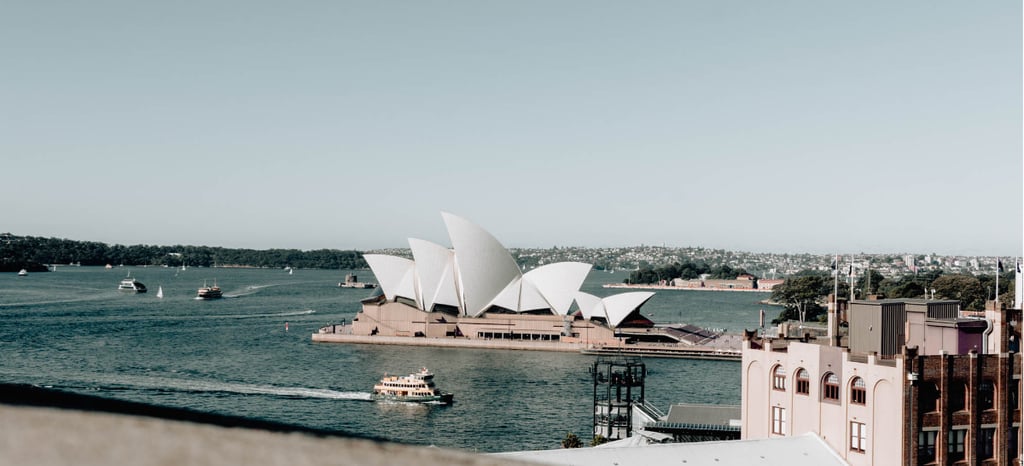 a view of a large building with a boat in the water. Opera House Sydney