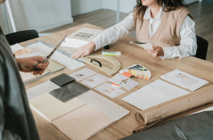Fabric samples, color swatches, design drawings spread across a table during a design consultation