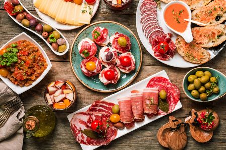 Traditional Spanish dishes including paella, tapas, and churros displayed on a rustic wooden table.