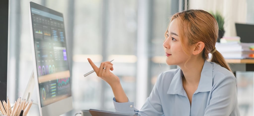 a woman sitting at a desk with a computer and a pen-ai integrated digital marketing