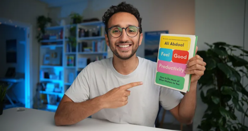 Ali Abdaal holding his book 'Feel Good Productivity'