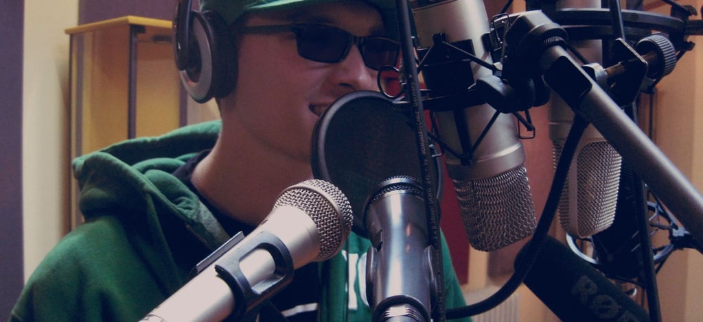 a man in a green hoodie and sunglasses is testing 6 microphones