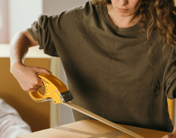 a women packing box with tape