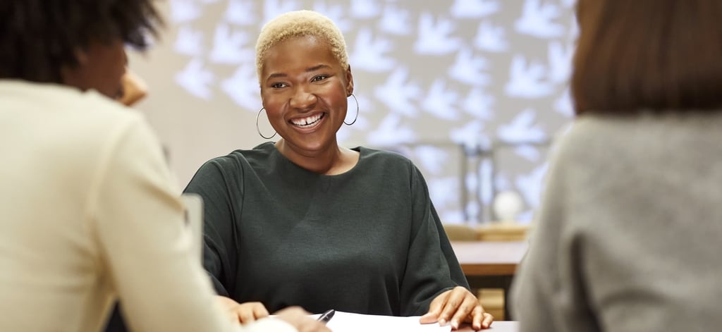 Una mujer afro con una camisa verde sonríe y habla con otras mujeres