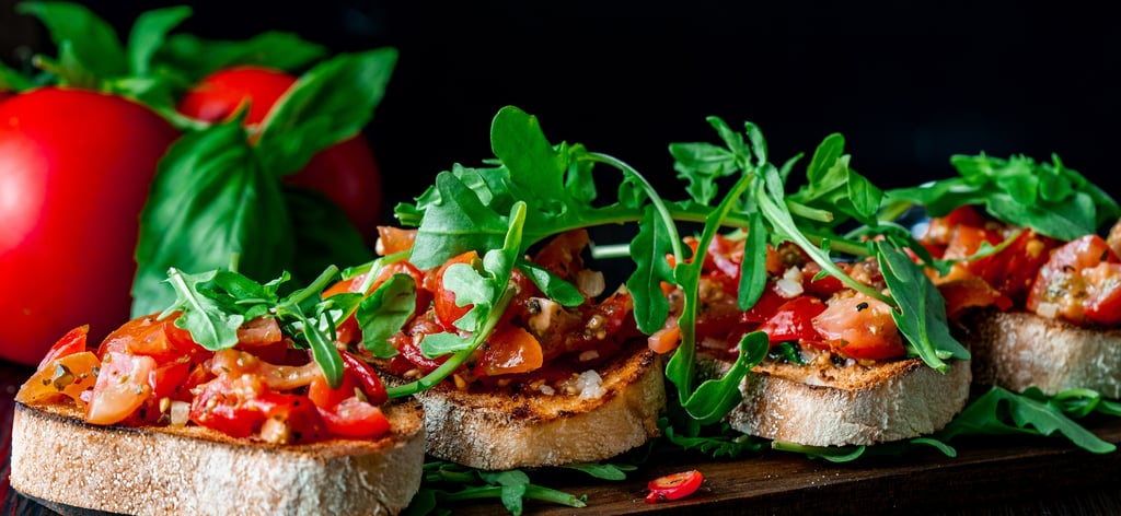 Traditionelle italienische Tomaten-Bruschetta mit frischem Rucola und Basilikum auf geröstetem Brot.