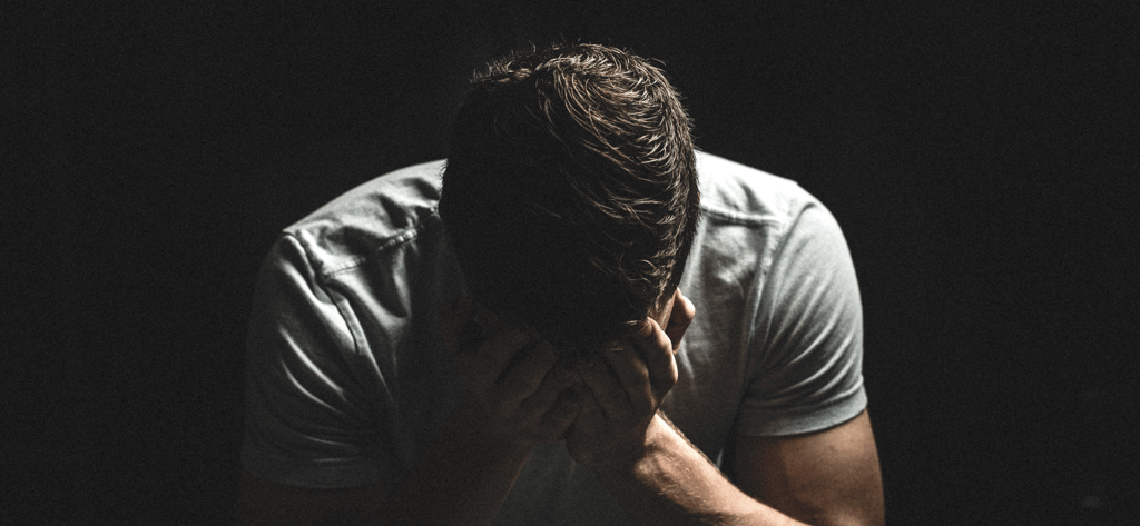 a man in a white shirt is holding his hands to his face