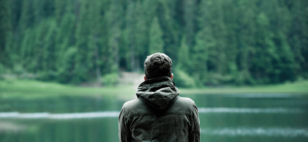 Man reflecting by a lake, symbolizing self-advocacy and confidence-building in ADHD adulthood