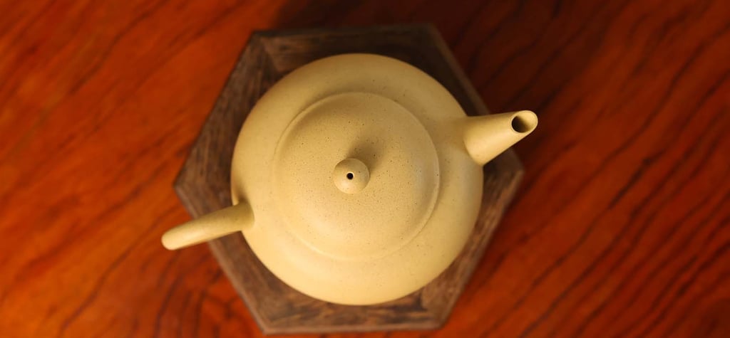 Overhead view of a light yellow teapot placed on a wooden stand