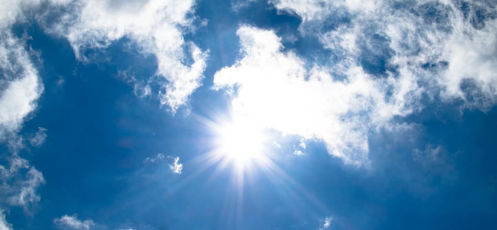 a plane flying through the sky with a sun shining through the clouds