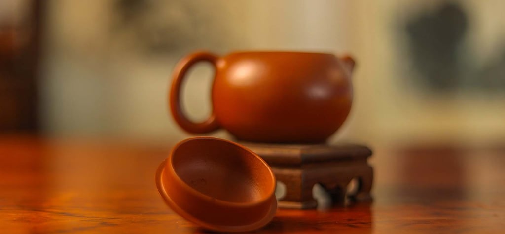 Brown teapot placed on a wooden stand, with the lid on the table