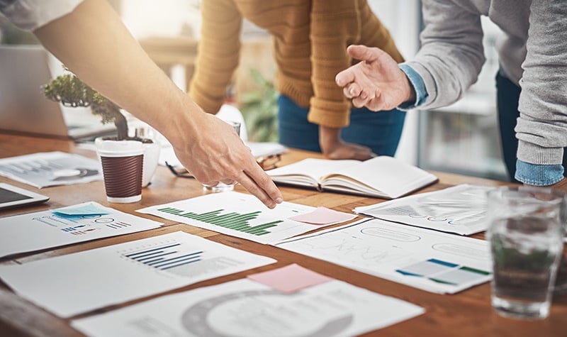 a group of people standing around a table with papers and papers