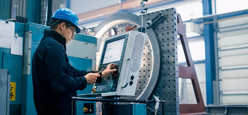 a man in a hard hat and hard hat with a laptop on a machine