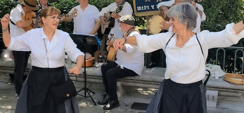 Two women dance a jota while an Escofolk band plays music