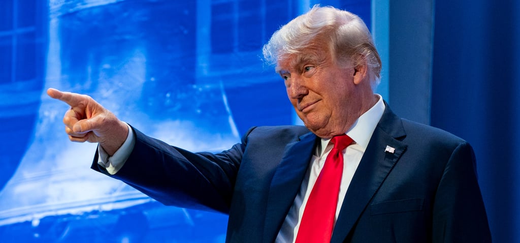 Donald Trump in a suit and tie is pointing at something