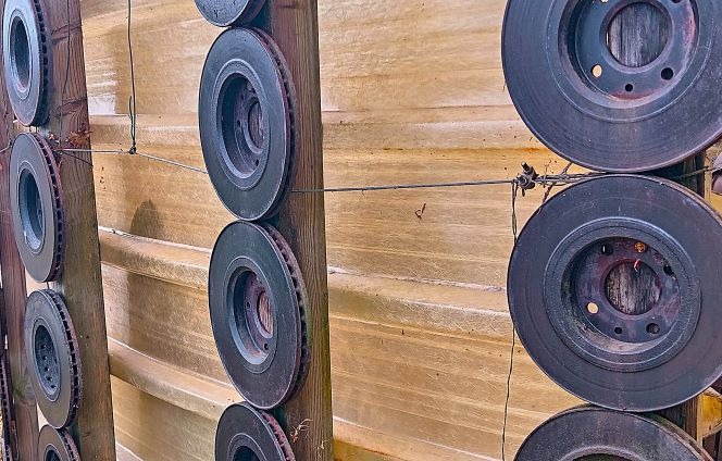 Used car brake rotors mounted on vertical wooden posts as a creative metal wall decoration.