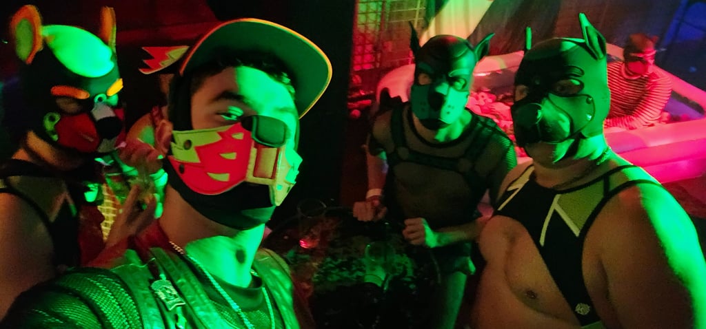 Friends posing in a club wearing pup masks.