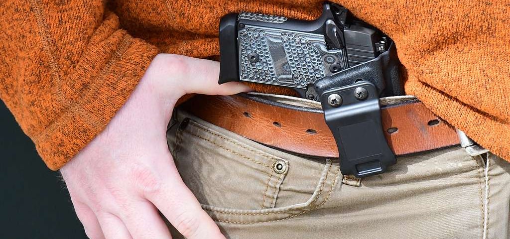 gun being concealed inside the waist band of a pair of pants