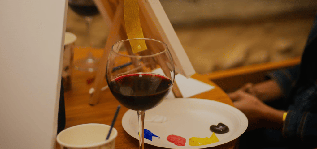 a pant and sip set up with with a glass of wine and paints