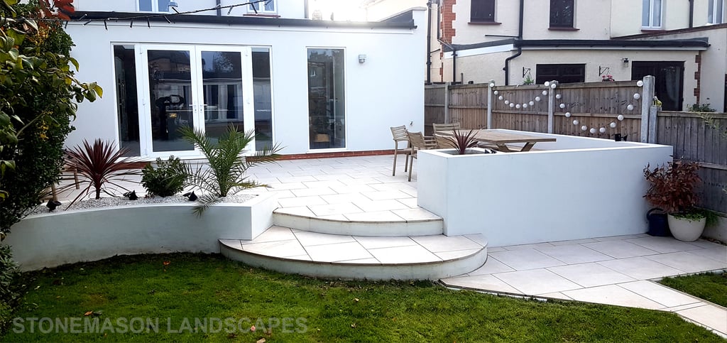Modern chic raised porcelain patio with white rendered walls and planters