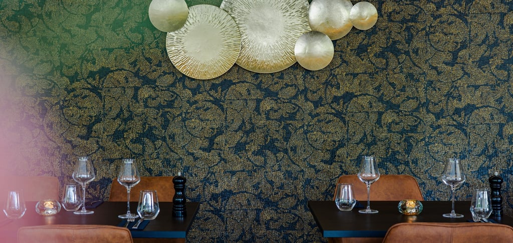 Elegante Restauranttische mit goldener Wandkunst und blauer Blumentapete.