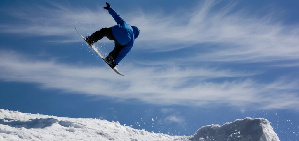 a snowboarder in mid air doing a trick on a snowy hill cerro catedral bariloche argentina