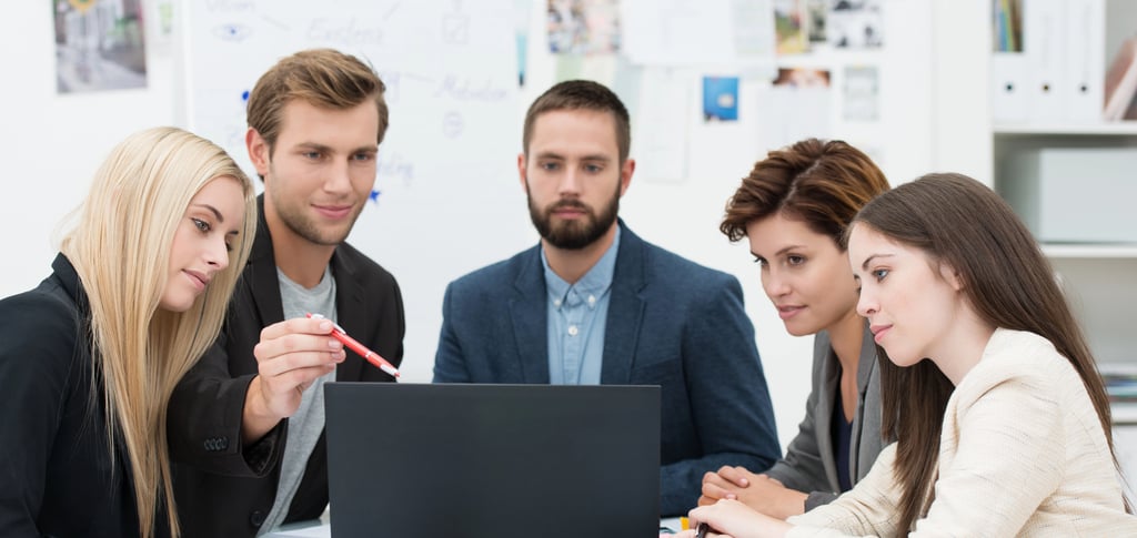 Diverse business team collaborating on a project during a corporate office meeting with a laptop.