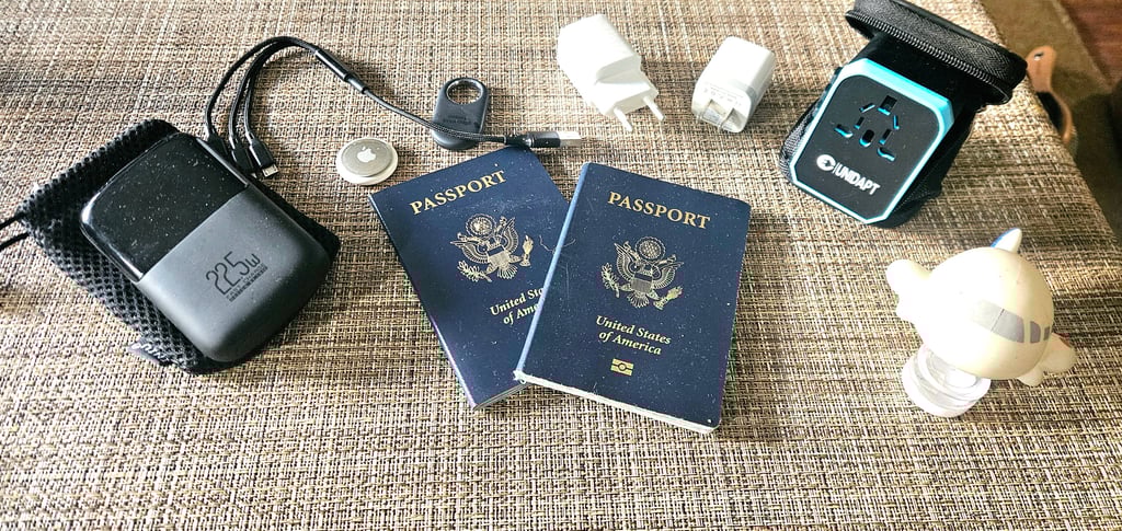 Portable charger, charging cables, luggage tracker, universal adapter and USB wall chargers on table