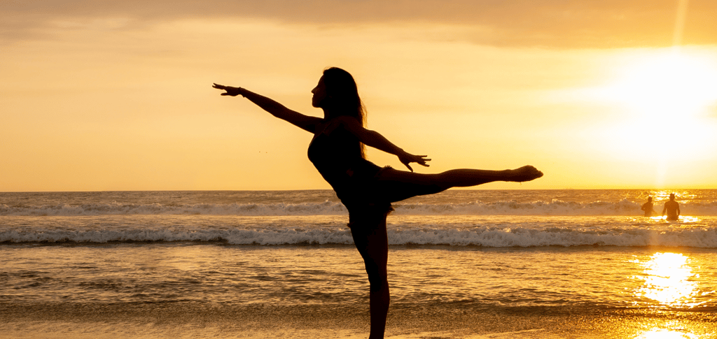 a woman is standing on a beach with her legs up in the air