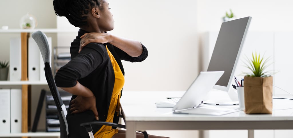 a woman sitting at a desk with a computer monitor and a monitor screen