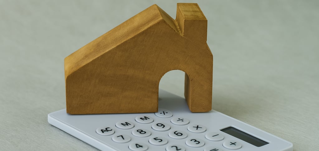 Un bloc en bois sculpté en forme de maison posé sur une calculatrice blanche, avec une vue rapproché