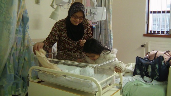 Doula Jannah with her 3rd born baby and her first born baby looking on to the baby. All ready to be