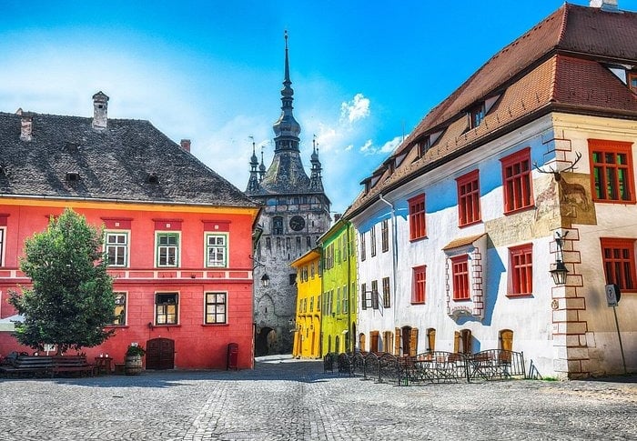 Colorful medieval buildings and the historic Clock Tower in Sighisoara Citadel, Romania.