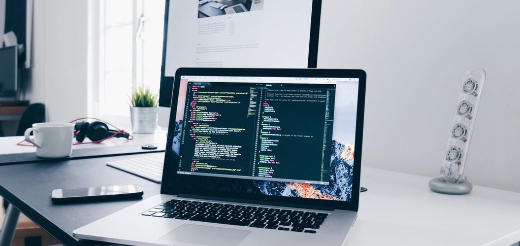 professional web design workspace with laptop showing website development code and design tools