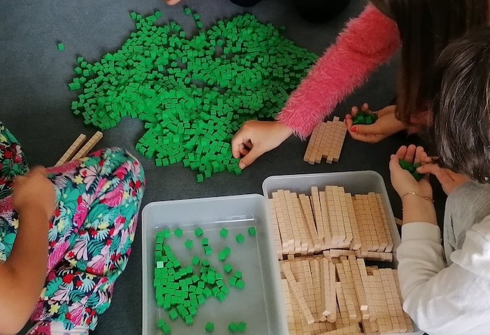 Kinder zählen Einerwürfel und wechseln immer zehn zu einer Zehnerstange.