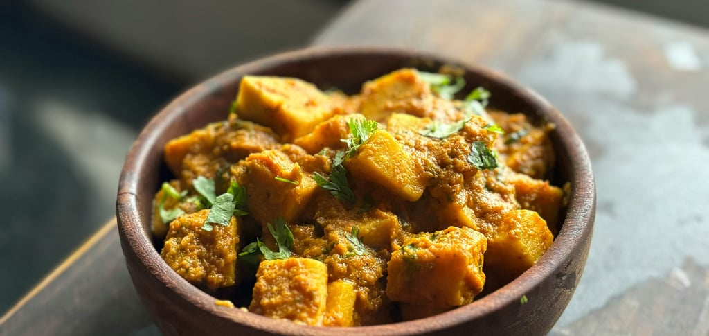 Chicken Tikka Masala served in a traditional copper bowl with rice and naan bread on the side.