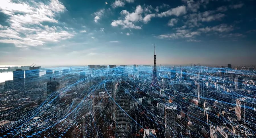 foto de una ciudad , se ven rallos celestes tipo laser recorriendo encima de la ciudad