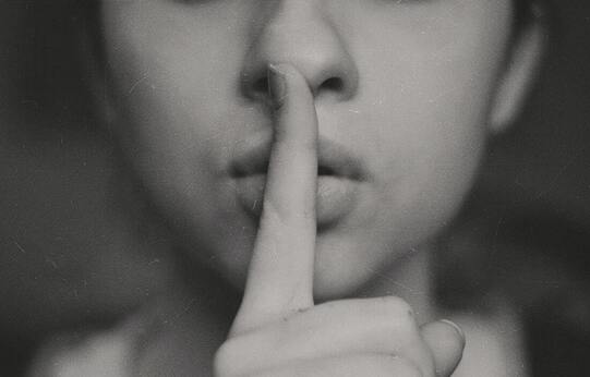 Woman with her forefinger over her lips indicating silence