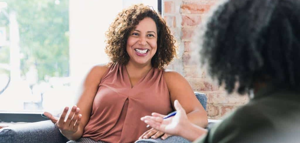 Smiling woman in a therapy session talking to her professional counselor in a modern office.