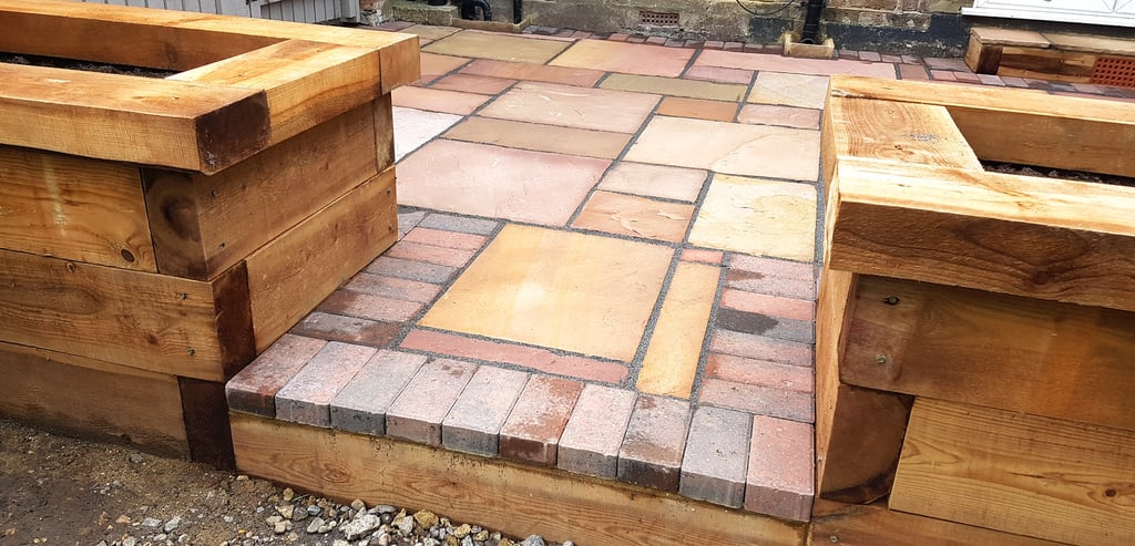 Colourful sandstone patio with raised wooden timber planter seating