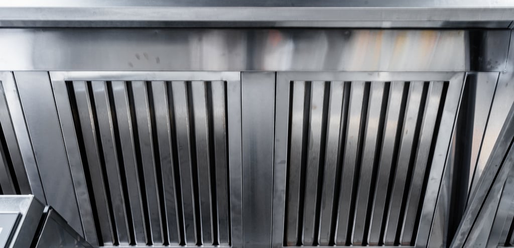 A stainless steel commercial kitchen exhaust hood with vertical slats designed for ventilation.